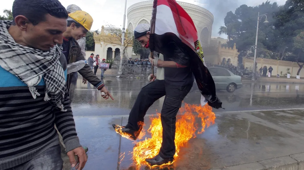Účastník demonstrace se snaží uhasit poté, co zapálil Mursího vlajku i sebe