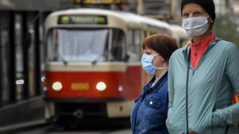 Cestující na zastávce v rouškách