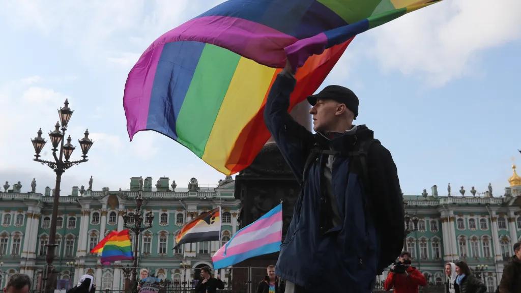 Muž mává duhovou vlajkou během shromáždění LGBT komunity v centru Petrohradu (snímek z roku 2019)