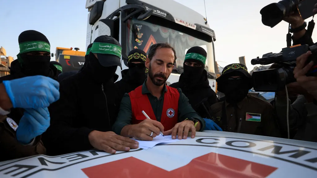 Člen Červeného kříže přebírá tělo, které bylo nalezeno palestinskými militanty z teroristického hnutí Hamás a Palestinského islámského džihádu, předtím než bude předáno Izraeli k určení, zda se jedná o tělo rukojmí, Pásmo Gazy, 3. prosince 2025