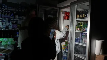 Lidé používají telefony a čelové svítilny při nákupu potravin v supermarketu během výpadku proudu ve španělské Barceloně