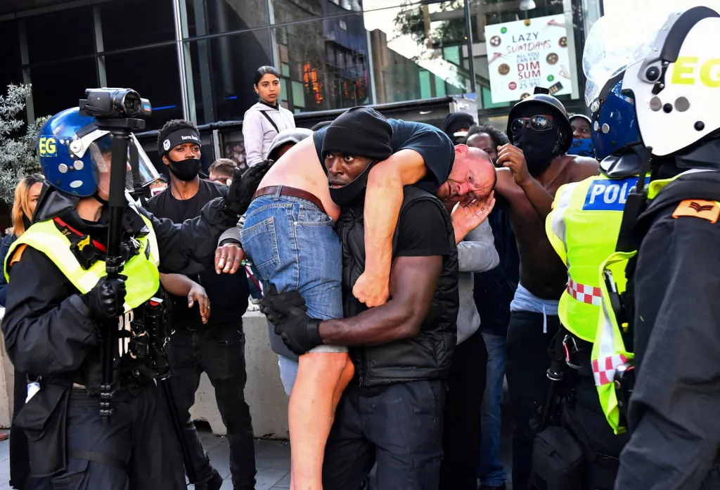 Smrt Afroameričana George Floyda vyvolala demonstrace po celém světě. Na snímku nese demonstrant Patrick Hutchinson z hnutí Black Lives Matter zraněného muže, který patří k nacionalistům. Ti během demonstrace stáli na druhé straně konfliktu. Fotografie vznikla poblíž stanice Waterloo v Londýně v Británii 13. června 2020