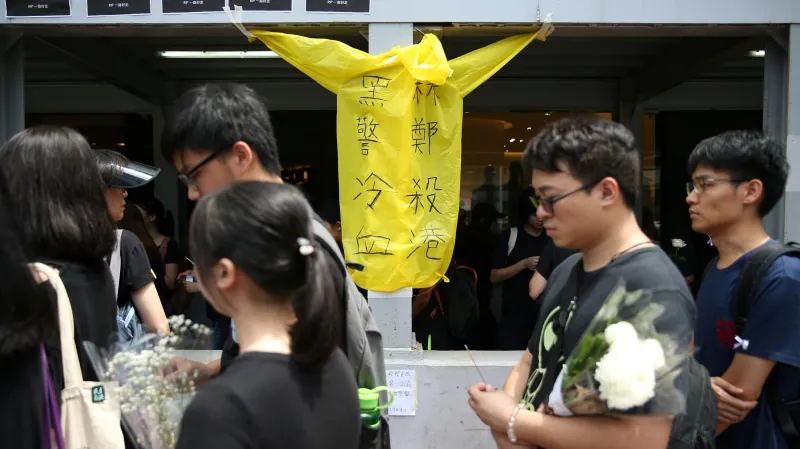 Lidé u památníku muže, který se zabil v sobotu, když se snažil pověsit transparent