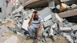 Palestinec sedí na troskách svého domu v Chán Júnis