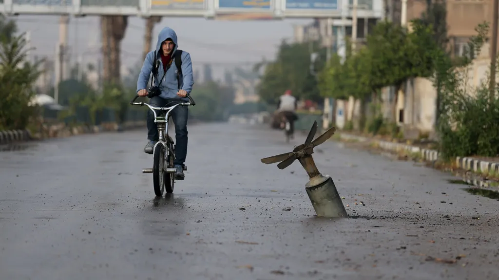 Rezident jezdí na kole v blízkosti toho, co podle aktivistů zbylo po bombě na předměstí Douma u Damašku