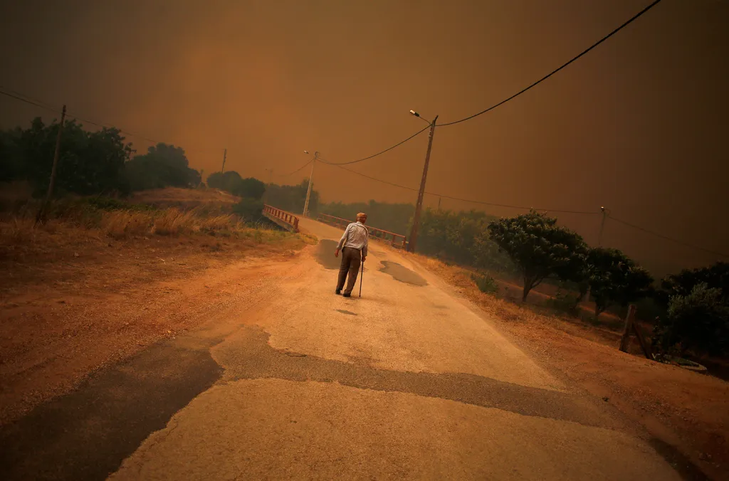 Muž na silnici před postupujícím lesním požárem poblíž města Silves v Portugalsku
