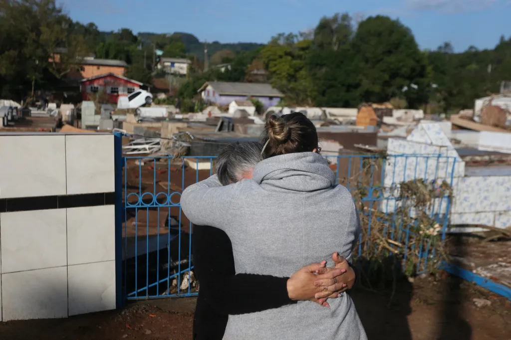 Dvě ženy se objímají před hřbitovem v Caraá