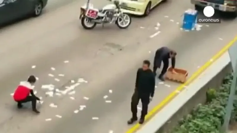 Lidé v hongkongské čtvrti Wan Chai sbírají rozsypané bankovky