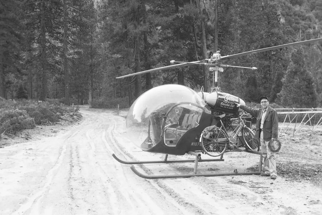 Zaměstnanec služby národních parků stojí vedle vrtulníku používaného k vyšetřování škod způsobených povodněmi v Národním parku Kings Canyon v okrese Fresno v Kalifornii v roce 1955