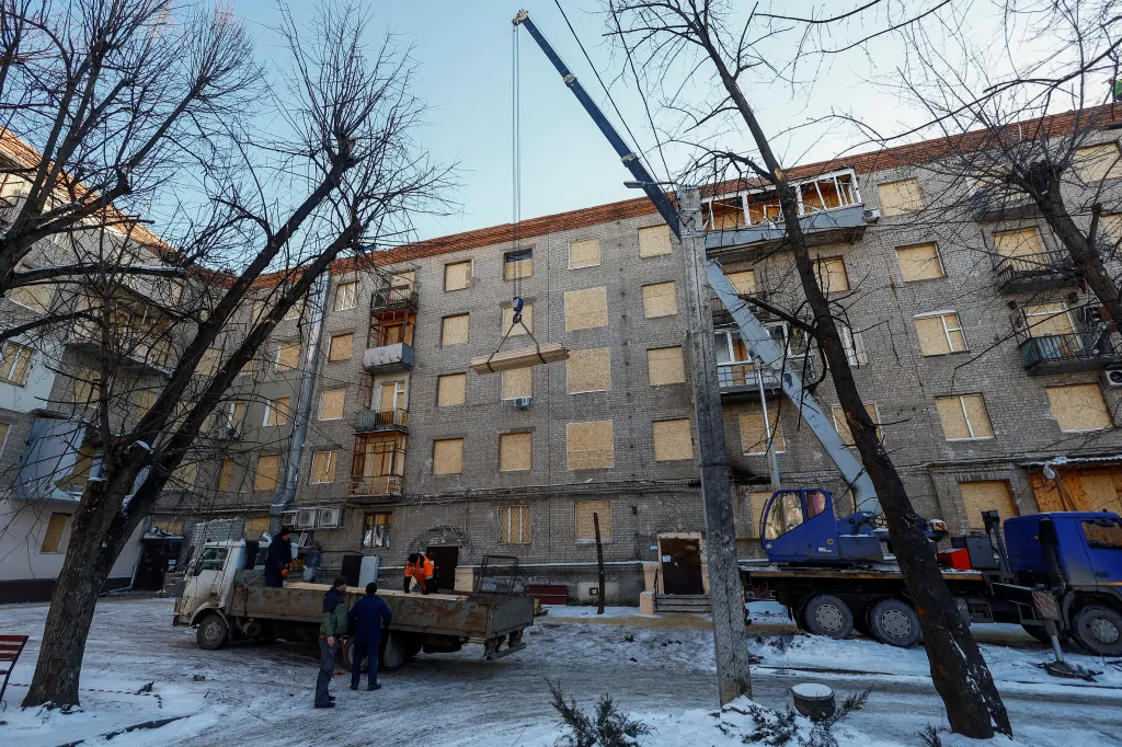 Dělníci opravují jeden z mnoha poškozených bytových domů (Foceno 13. ledna 2024)