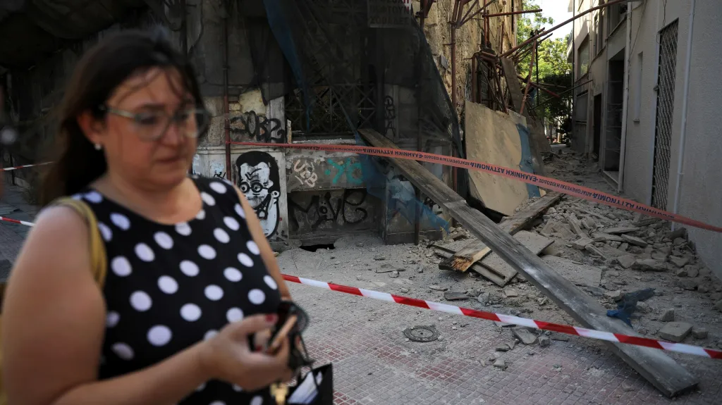 Žena prochází v Aténách kolem budov, které poničilo zemětřesení