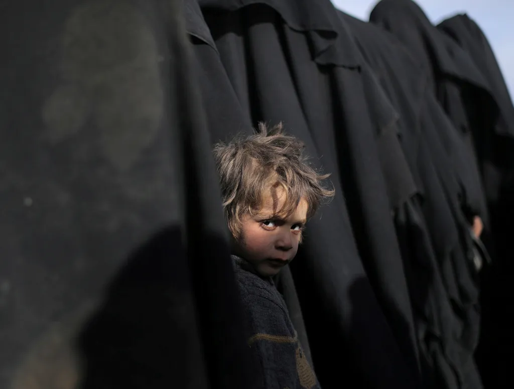 Chlapec v řadě zahalených žen u vesnice Baghúz, kde probíhá bitva o poslední výspu Islámského státu