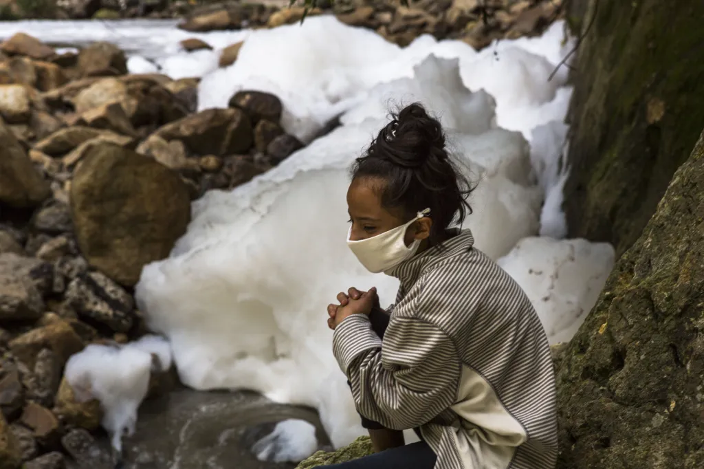 Jedenáctiletá Jeslin Enriquezová sedí na břehu znečištěné řeky El Naranjo. Její rodina nemá přístup k pitné vodě už přes osm let. Musí si proto vodu dovážet z jiných míst v regionu