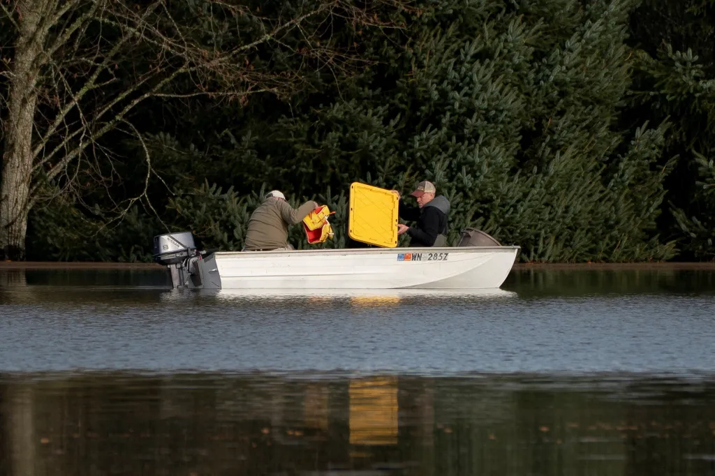 Muži loví z vody věci, které uplavaly z blízké farmy ve Fall City na severozápadě USA