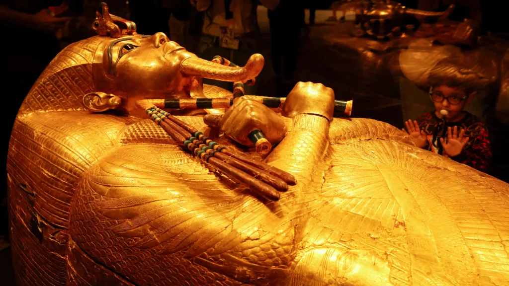 Dítě se dívá na zlatou rakev staroegyptského faraona Tutanchamona