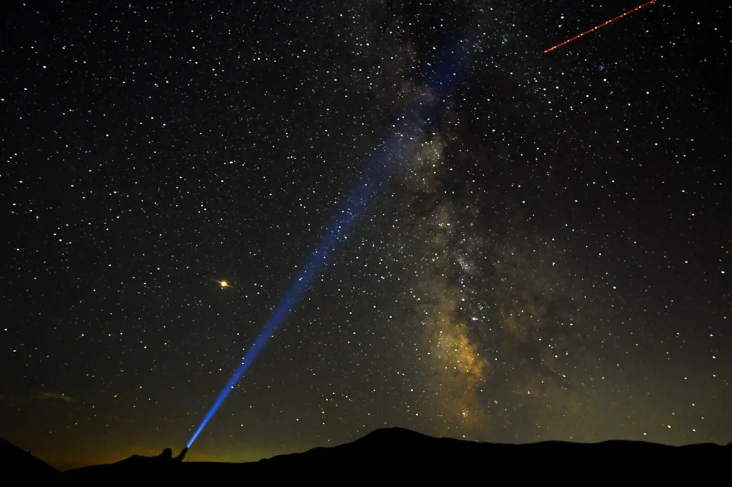 Muž ukazuje laserovým paprskem na Mléčnou dráhu během pozorování roje Perseid v makedonském národním parku Mavrovo.