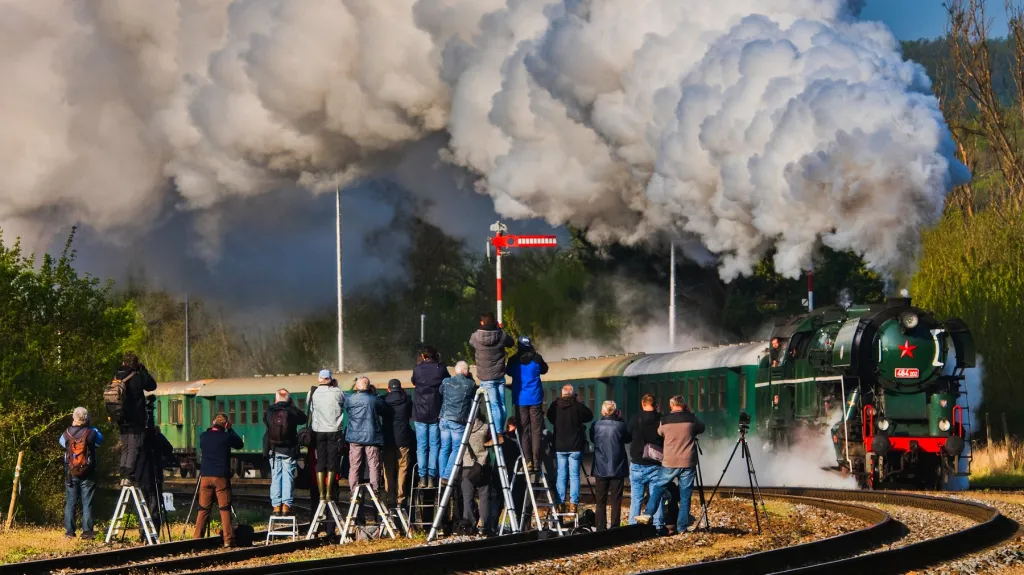 Skupina fotografů snímající parní lokomotivu