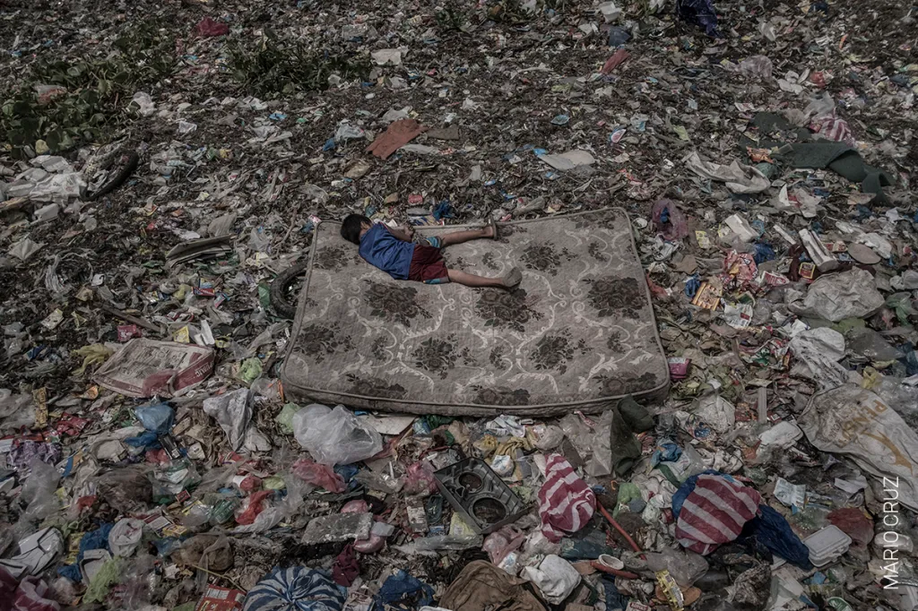 Nominace na vítěznou fotografii v kategorii ŽIVOTNÍ PROSTŘEDÍ. Mário Cruz – Chlapec leží na matraci uprostřed odpadků ve filipínské řece Pasig