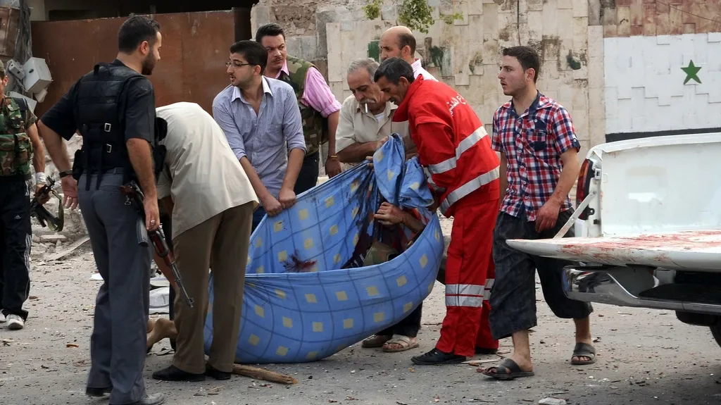 Muži odnášejí tělo oběti výbuchu v Aleppu