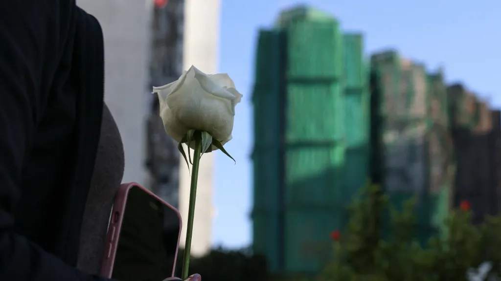 Žena uctívá památku obětí požáru v bytovém komplexu v Hongkongu