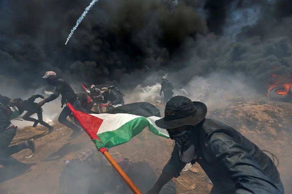 Palestinští demonstranti utíkají před sprchou slzných granátů na hranici Gazy s Izraelem při protestech proti přesunutí americké ambasády z Tel Avivu do Jeruzaléma