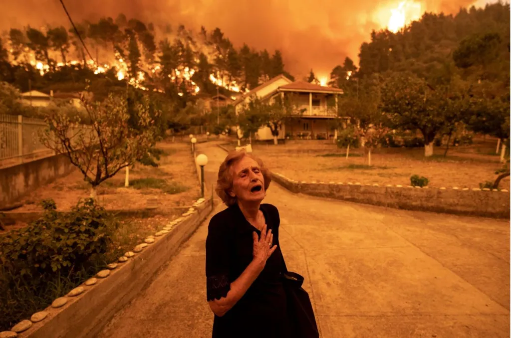 Vítězná fotografie v kategorii Evropa – singles (jednotlivé). Plačící žena, k jejímuž domu se blíží mohutný požár. Ten vypukl v srpnu roku 2021 na ostrově Evia v Řecku