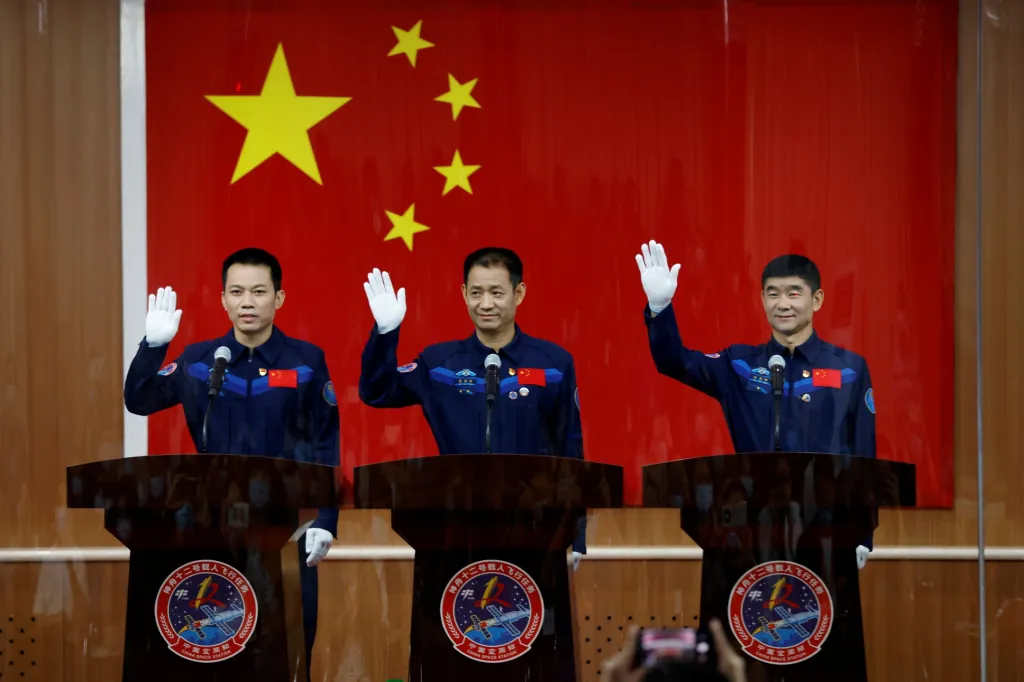 Čínští astronauti zdraví za skleněnou stěnou zástupce médií před startem vesmírné lodi Šen-čou 12. Čína ve čtvrtek úspěšně dopravila tuto posádku na svou nově budovanou vesmírnou stanici