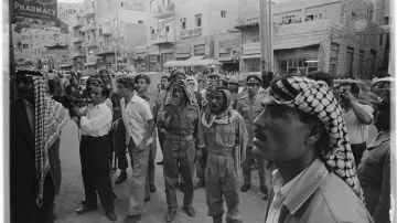 Dav mužů a vojáků si čte zprávu o svržení krále Fajsala II. 14. července 1958.