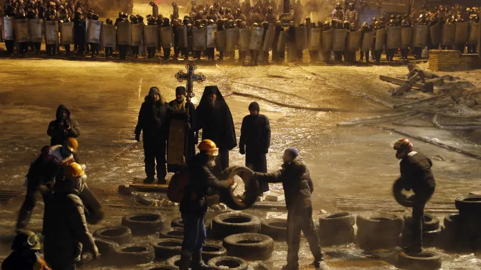 Demonstranti odstraňují z ulic Kyjeva pneumatiky před modlitbou pravoslavných kněží