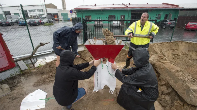 Dobrovolníci plní pytle pískem na ochranu před záplavami 29. června 2020 v Dolních Ředicích na Pardubicku, kde se kvůli silným dešťům vylil z břehů Ředický potok.