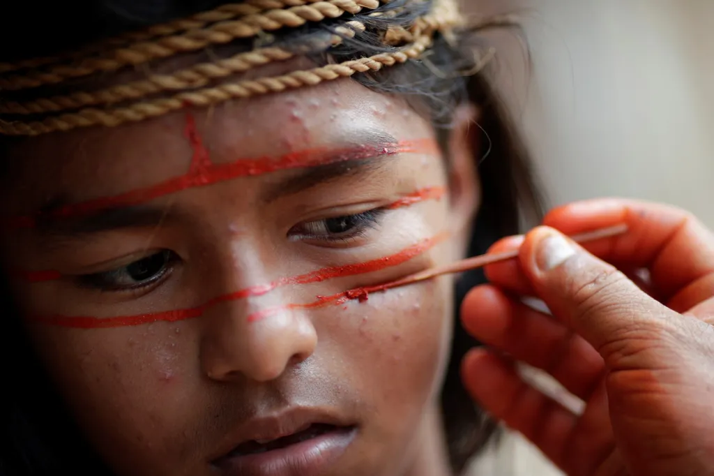 Domorodý muž z kmene Mura maluje tvář mladého hocha ve vesnici Itaparana poblíž města Humaita