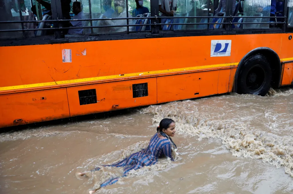 Několik dětí využilo zatopené ulice po silných deštích v indickém Novém Dillí jako zábavnou vodní atrakci