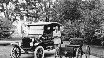 Henry Ford pózuje na fotografii z archivu své společnosti Ford Motor mezi čtyřkolkou z roku 1896 a jubilejním automobilem značky Ford model T, který překonal hranici 10 milionů vyrobených vozů.