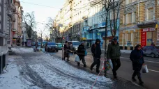 Obyvatelé Charkova prochází kolem uzavřeného chodníku před zničeným bytovým domem (Foceno 13. ledna 2024)