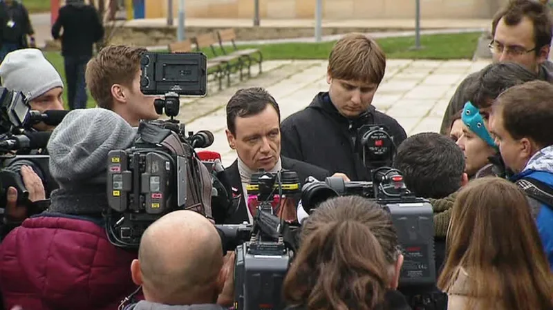 Rath mluví k novinářům na náměstí v Hostivici