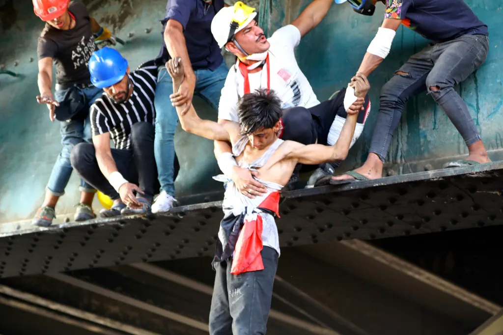 Iráčtí demonstranti pomáhají chlapci zasaženému slzným plynem během probíhajících protivládních protestů v Bagdádu