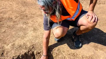 Archeolog Matěj Forst popisuje keramické úlomky nalezené při průzkumu na jednom z úseků budované dálnice D6