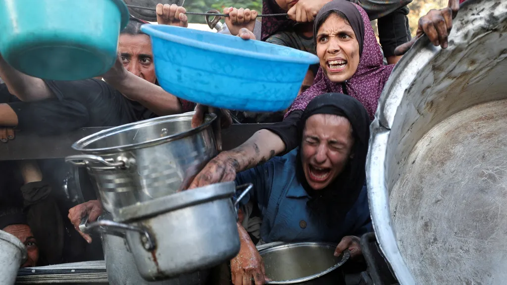 Palestinci žádající o jídlo z charitativní kuchyně v Gaze