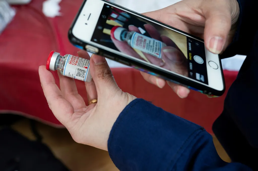 Zdravotní sestra kontroluje šarži vakcíny Moderna prostřednictvím mobilní aplikace