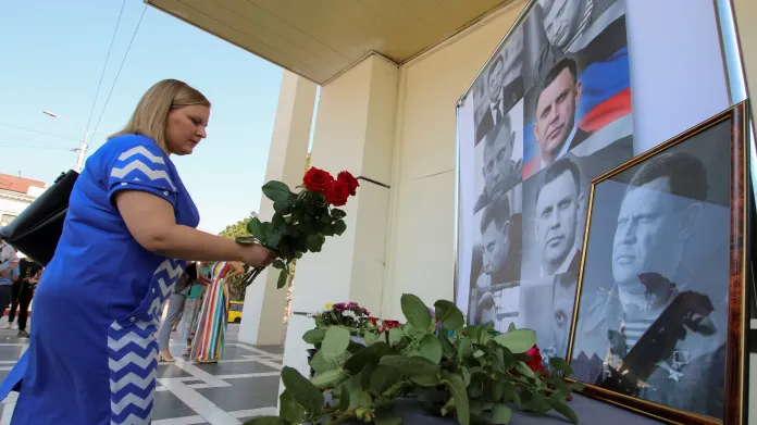 Obyvatelka Krymu nese květinu k fotkám zavražděného lídra doněckých povstalců Alexandra Zacharčenka