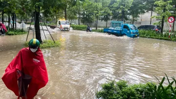 Lidé projíždějí zaplavenou ulicí v Hanoji