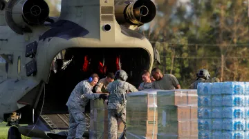 Vojáci vykládají vodu a potraviny pro lidi v obci izolované povodní z vrtulníku CH-47 Chinook