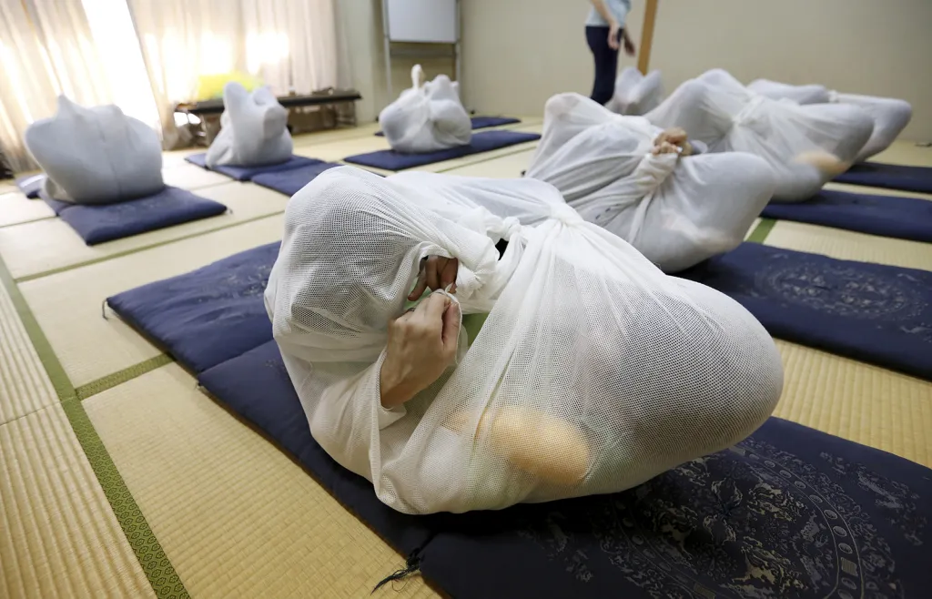 Účastníci kurzu metody zvané Otonamaki (zavinování dospělých). Jde o novou formu psychoterapie, v níž jsou lidé v japonském městě Asaka zabalováni do látky připomínající dětskou plenku, čímž mají řešit problémy špatného držení těla a chronické ztuhlosti svalů.