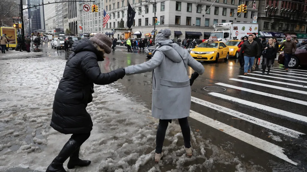 Lidé se snaží přejít v New Yorku namrzlou a zasněženou silnici