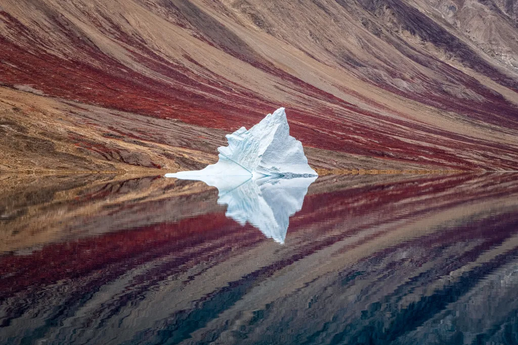 Vítěz kategorie LANDSCAPE: Ice Reflections. Osamělý ledovec poblíž stěny fjordu v národním parku na severovýchodě Grónska. Zrcadlením ve vodní hladině působí jako abstraktní malba