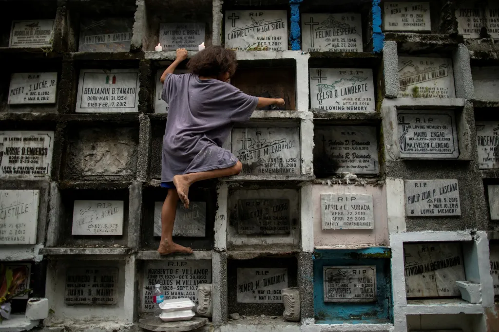 Dítě čistí roztavený vosk ze svíček z hrobu na manilském hřbitově před svátkem Všech svatých. Filipíny se potýkají s nárustem onemocnění covid-19 a v pátek došlo v zemi k celkovému lockdownu, který má dopad i na uzavření hřbitovů