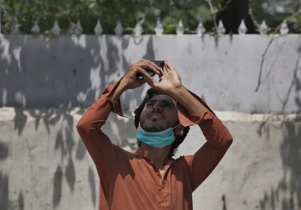 Muž se snaží vyfotografovat částečné zatmění slunce v Pákistánu