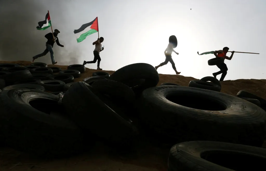 Palestinští demonstranti na hranicích Gazy a Izraele utíkají před izraelskými vojáky