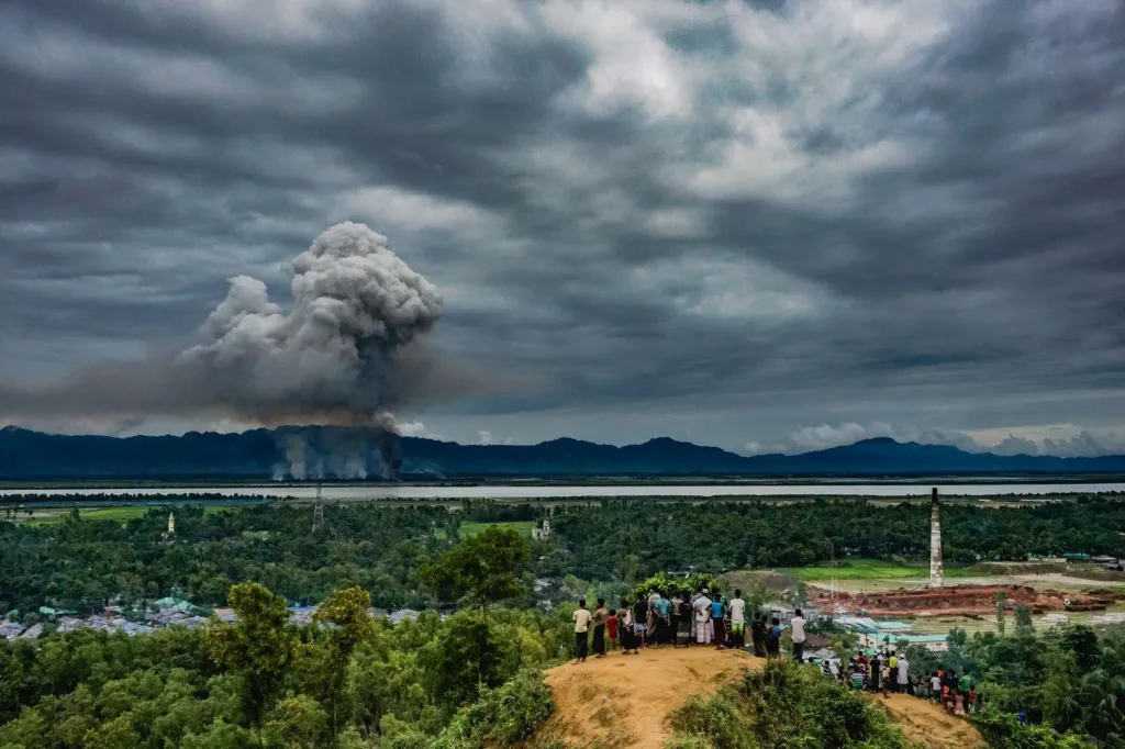 Třetí cena v kategorii Reportáž. Podívaná na hořící domovy. Skupina rohingských uprchlíků na thajské straně hranice sledují dým ze zapálené rohingské vesnice v Barmě.