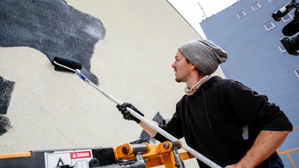 Výtvarník Lukáš Veselý vytváří malbu na domě